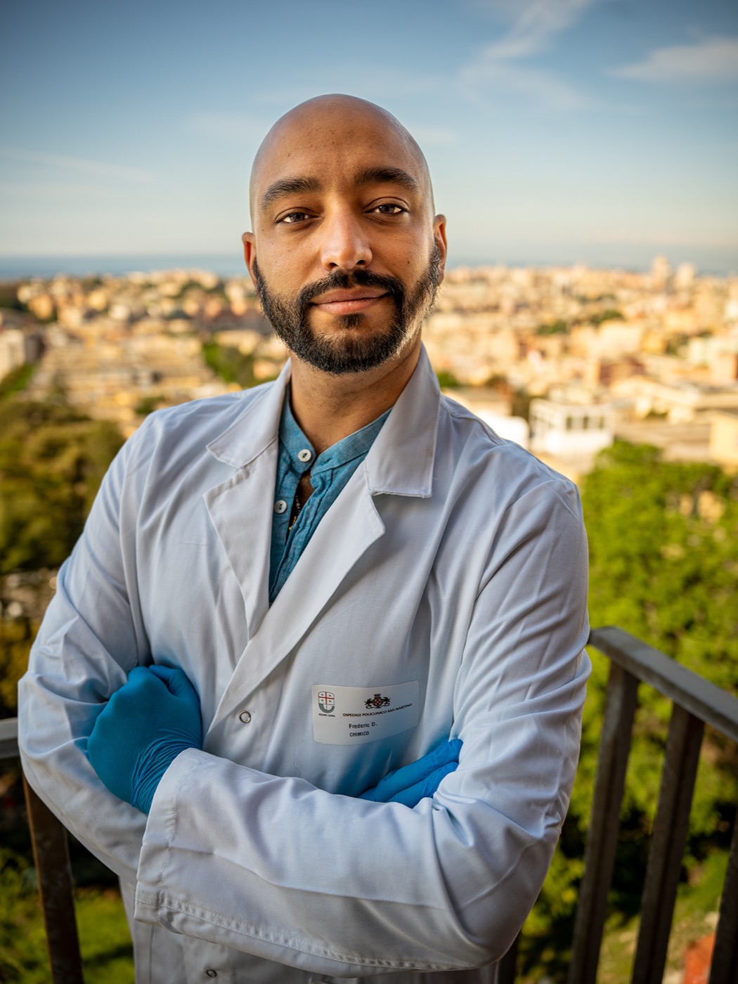 Fred Dante David outdoors in a lab coat, with the Genova skyline in the background