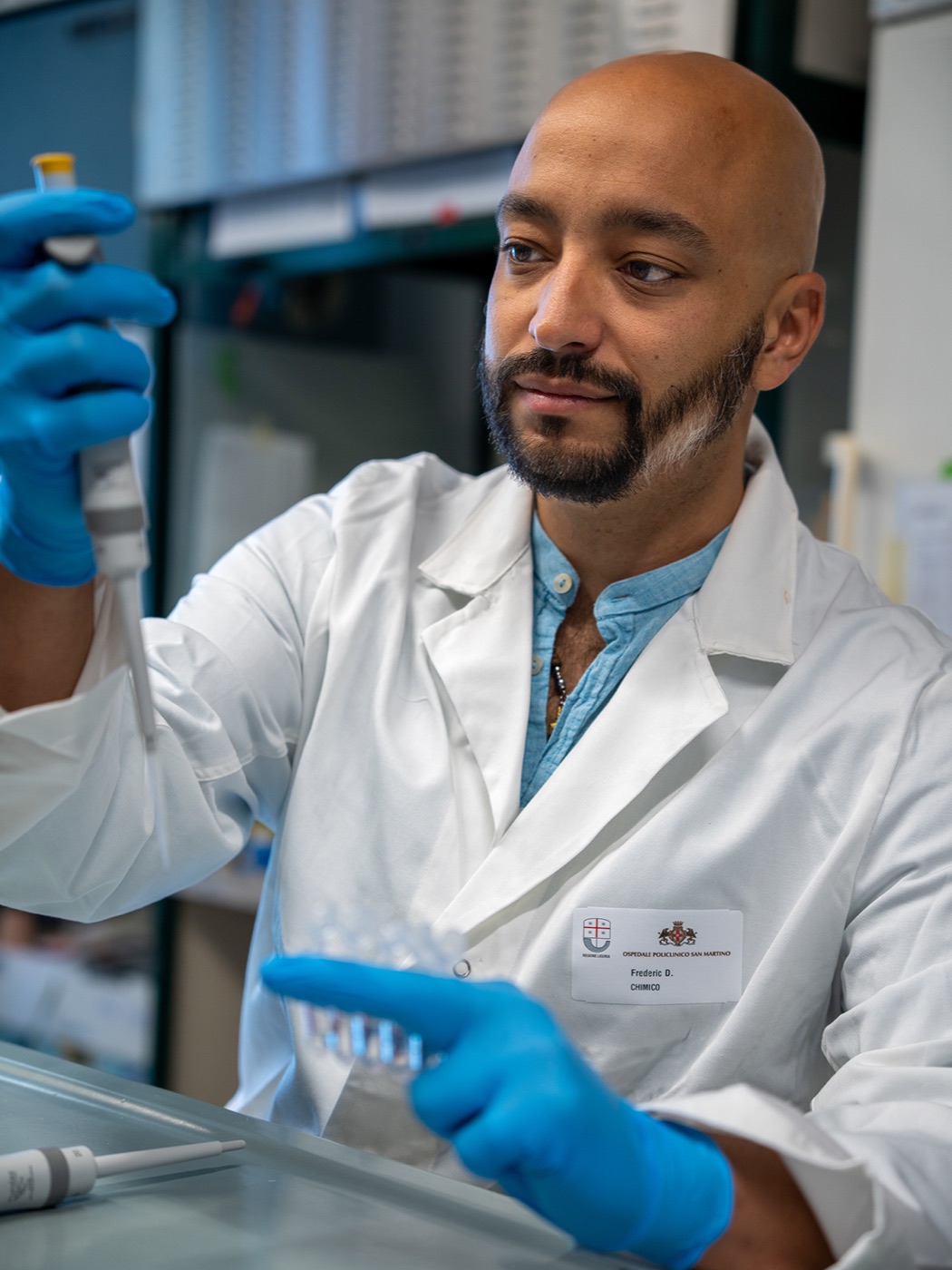 Fred Dante David in a lab coat and blue gloves, handling a sample in the laboratory